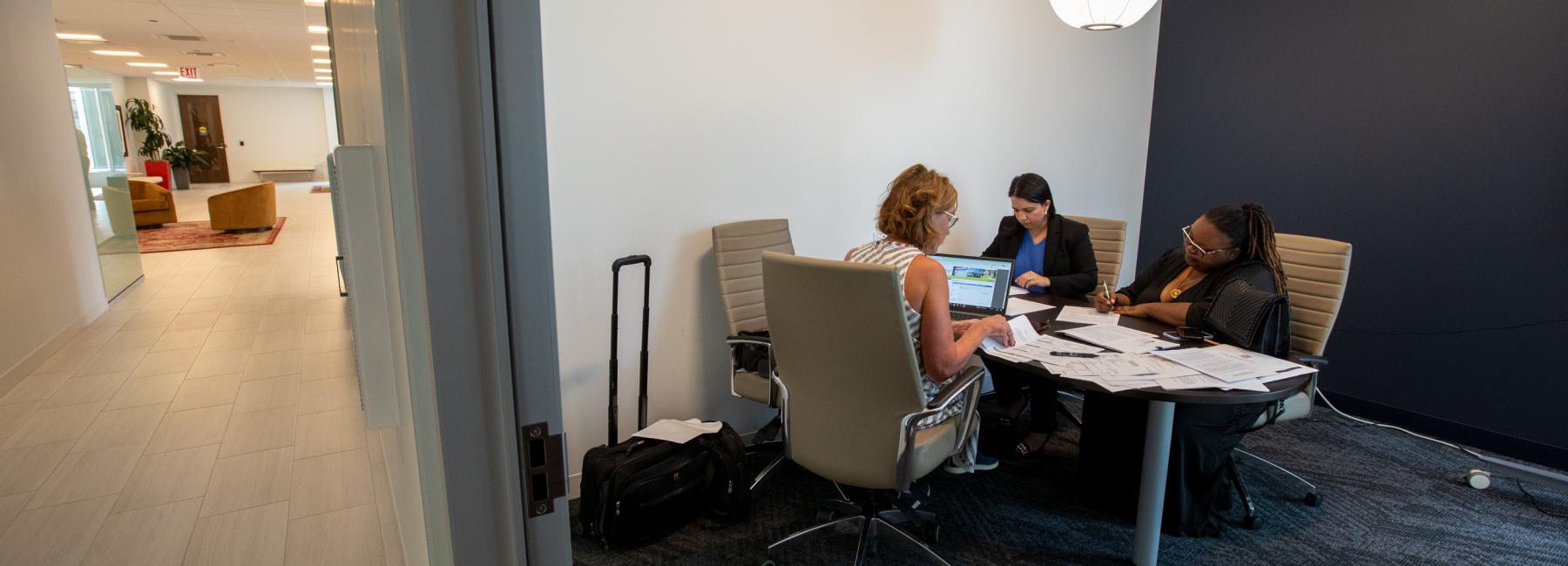 A zoomed out view of a conference room where a new homeowner is signing papers with the realtor.