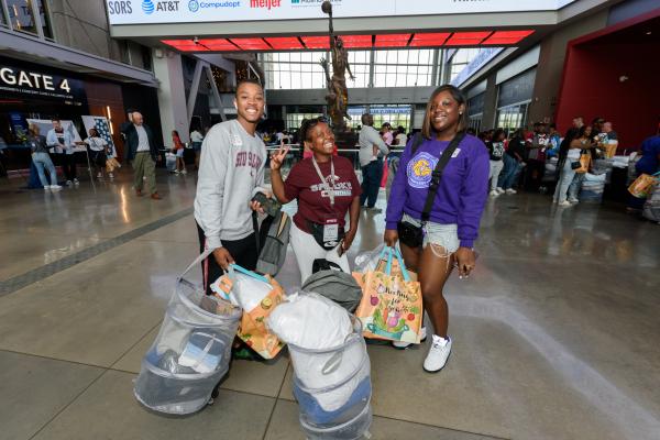 Teens carrying college supplies posing for a picture.