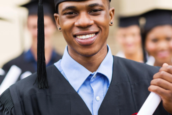 Boy holding diploma while wearing graduation cap and gown.