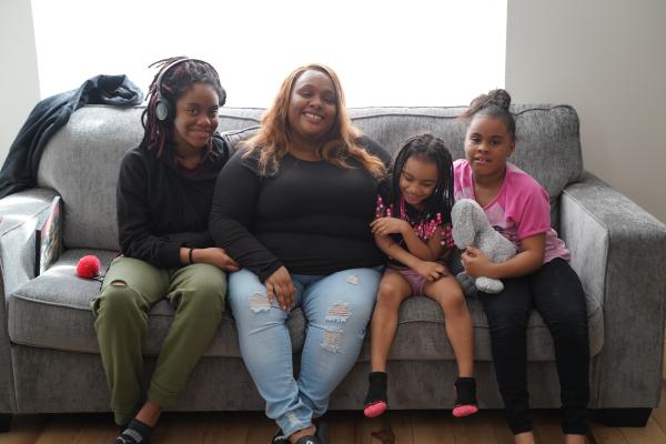 Shavon Nowell, center, sits with her three daughters on their sofa in their new home. 