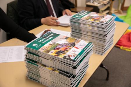 A stack of HQS (Housing Quality Standards) guidebooks on a table a HCV resource fair.