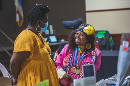 A woman in a wheelchair talking to woman in a yellow dress at a B2B networking event.