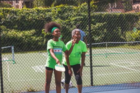 A CHA senior resident and youth enjoy a game of pickleball together 